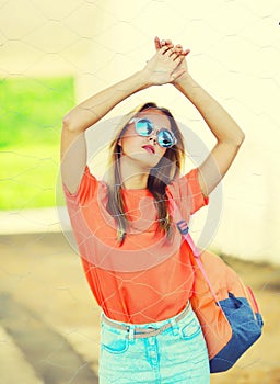 Summer portrait of stylish blonde young woman wearing backpack, sunglasses in the city