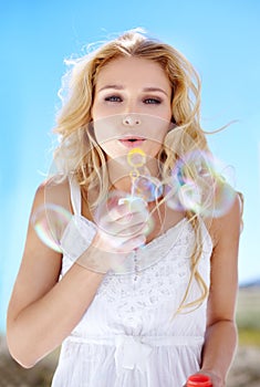 Summer, portrait and a woman blowing bubbles for happiness, fun and playful in nature. Beautiful, spring and a young