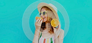 Summer portrait woman eating and holding in her hands two slices of orange fruit in straw hat on a colorful blue background