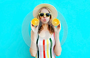 Summer portrait woman holding in her hands two slices of orange fruit in straw hat on colorful blue