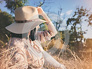 Summer portrait of young hipster woman lying in a grass on sunny day.Woman in hat, kinfolk concept,pretty face,dreaming