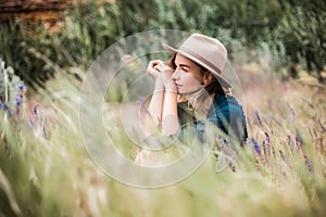 Summer portrait of young hipster woman sitting in a grass on sunny day