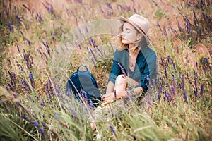 Summer portrait of young hipster woman sitting in a grass on sunny day
