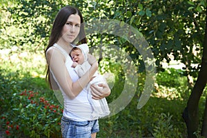 Summer portrait of a young mother with a newborn child