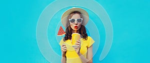 Summer portrait of young woman drinking juice with lollipop watermelon on blue background