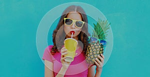 Summer portrait young woman drinking a juice with pineapple wearing a sunglasses on a blue background