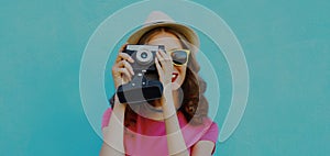 Summer portrait young woman photographer with vintage film camera on a blue background