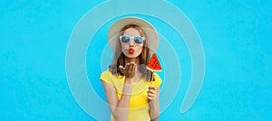 Summer portrait of young woman with sweet juicy lollipop or ice cream shaped slice of watermelon wearing straw hat on blue