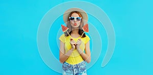 Summer portrait of young woman with sweet juicy lollipop or ice cream shaped slice of watermelon wearing straw hat on blue