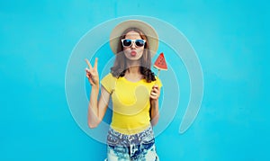 Summer portrait of young woman with sweet juicy lollipop or ice cream shaped slice of watermelon wearing straw hat on blue