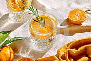 Summer refresh orange cocktail with ice, herb and ripe bio citrus fruits on linen tablecloth. Organic Sicilian oranges