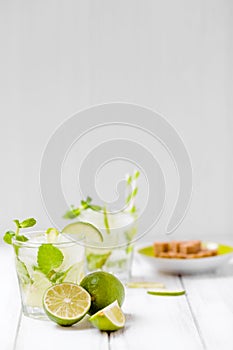 Summer refreshing cocktail caipirinha with lime and mint on white wooden vintage background.