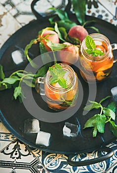 Summer refreshing cold peach ice tea in glass jars