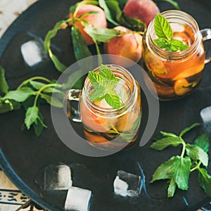 Summer refreshing cold peach ice tea in jars, square crop