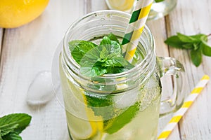 Summer refreshing detox cocktail. Water with lemon, mint and ice in mason jar on wooden board. Rustic style. Close up.