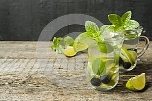 Summer refreshing drinks lemonade or cocktail Mojito with lime fresh mint blueberry ice. Wooden background