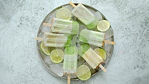 Summer refreshing homemade lime popsicles with chipped ice over stone background