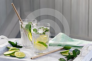 Summer refreshing mojito cocktails with lime and mint on a white wooden tray