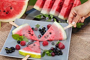 Summer refreshing snack concept with hand taking watermelon slice from a fruit plate