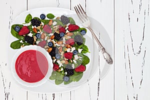 Summer refreshing spinach mixed berry salad with pumpkin and sunflower seeds, almonds, feta cheese and red raspberry vinaigrette