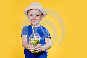 Summer refreshment. Cold beverage. Little boy with plastic cup of fresh lemonade