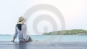 Summer relaxation of asian woman take it easy happily sitting resting on pier or sea deck peacefully with ocean water