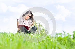 Summer relaxation concept with beautiful girl sitting on meadow