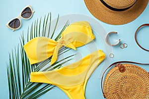 Summer rest concept. Top view photo of sunhat gold rings bracelet stylish sunglasses yellow bikini round rattan bag and palm