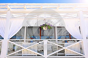 Summer restaurant under a canopy. Dining table for a romantic lunch on the beach against the sky. Rest and quiet life on the beach