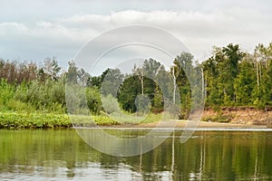 Summer river landscape with uninhabited coast and sky with clouds