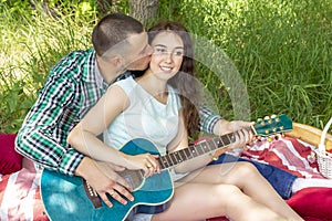 Summer romantic picnic. guy shows the girl how to play the guitar. couple sitting on the grass