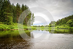 Summer rural landscape on the river on a cloudy day