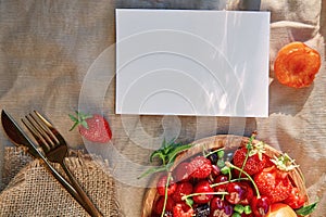 Summer rustic stationery card mockup with hard shadows, sunlight and fresh seasonal fruits, berries. Top view, flat lay