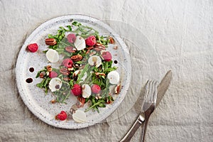 Summer salad with arugula, raspberries, mozzarella cheese and pecan nuts