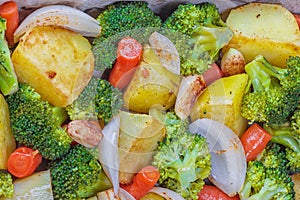 Summer salad with broccoli, carrots,white onion, garlic and potatoes sprinkled with spicy herbs and parsley close up on a plate