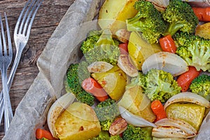 Summer salad with broccoli, carrots,white onion, garlic and potatoes sprinkled with spicy herbs and parsley close up on a plate