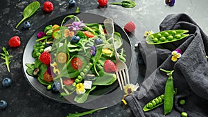 Summer salad with edible flowers, spinach, blueberries, raspberry, sweet peas, cherry tomatos and feta cheese