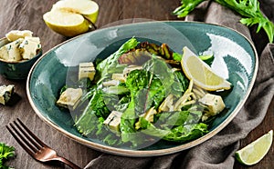 Summer salad with leaves of lettuce, spinach, apple, blue cheese and lemon juice in plate on wooden background. Healthy vegan food