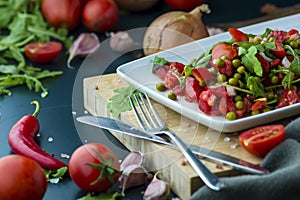summer salad, tomatoes, green peas, arugula, onion, olive oil, garlic, hot pepper fork knife bamboo cutting board pastel green