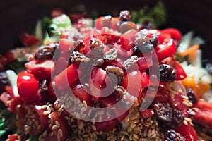 Summer salad with tomatoes seeds and sultana in a wood bowl