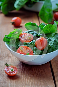 Summer salad with tomatoes in white plate on wood table