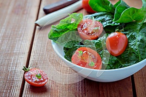 Summer salad with tomatoes in white plate on wood table