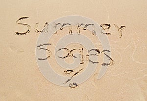 Summer sales written on sand - seasonal discount shopping