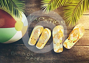 Summer sandals with beach ball on wood