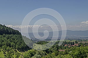 Summer scene with mountain glade, forest and residential district of bulgarian Zhelyava village, Sofia region, Balkan mountain