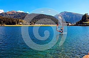Summer scenery of Lake Davos on a bright sunny day with windsurfers poising sailboards on the turquoise water under blue clear sky photo
