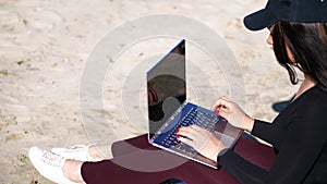 Summer,sea beach. sunrise, beautiful woman in a black cap, blaser is working on laptop