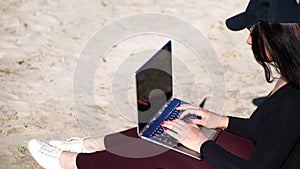 summer,sea beach. sunrise, beautiful woman in a black cap, blaser is working on laptop