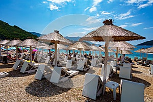 Summer sea coast in the resort town, beach with sun loungers and umbrellas, blue sunny sky, background of travel during vacation