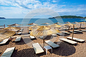 Summer sea coast in the resort town, beach with sun loungers and umbrellas, blue sunny sky, background of travel during vacation